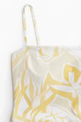 Traje de baño enterizo con estampado de hojas en tonos amarillo y blanco, breteles finos y escote recto.