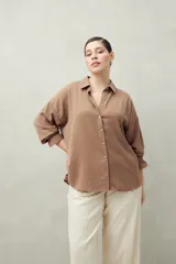 Camisa negra de manga larga con cuello clásico y botones frontales. El tejido presenta una textura arrugada o plisada, y los puños tienen un detalle fruncido o elástico.