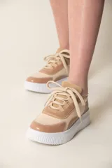 Zapatilla de cuero vacuno en tonos beige y verde, con suela blanca y detalles de diseño moderno.