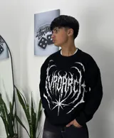 Sweater negro de corte holgado con estampado frontal de araña y texto en blanco.