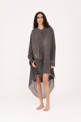Camisa larga de fit amplio, color gris oscuro con efecto desgastado/lavado, cuello mao y cierre frontal de botones. Presenta mangas largas y un bajo asimétrico con terminación deshilachada.