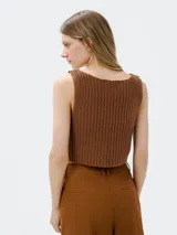 Musculosa color crema tejida a crochet con escote en V y cierre frontal con gancho metálico.