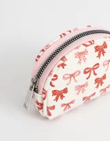 Monedero pequeño de cuerina color blanco con estampado de moños rojos y rosados, y cierre de cremallera.