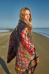 Poncho de cuero ovino con corte de chaqueta y mangas tejidas en lana con diseño geométrico multicolor. Talle único.