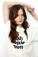 Remera blanca de corte amplio con estampado frontal de la frase "oui mais non" en color negro.