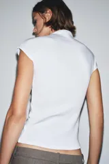 Top sin mangas, color marrón topo, con cuello alto y corte recto. Presenta un tejido de punto fino y mangas sisa con caída.