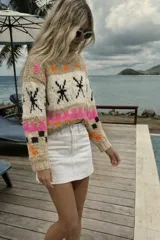 Sweater de lana merino color crema con cuello alto y diseño con motivos geométricos en amarillo, naranja, violeta y negro.