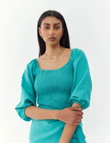 Top turquesa con escote cuadrado, mangas abullonadas y cuerpo fruncido.