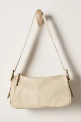 Bolso bandolera color crema, de cuero, con correa ancha ajustable con hebilla dorada.