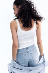 Musculosa blanca de algodón acanalado con breteles finos y escote redondo pronunciado con ribete de encaje.