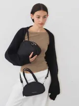 Cartera negra de lona semi impermeable con cierre metálico y correa larga regulable.