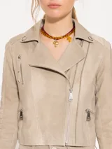 Chaqueta de cuero ovino color beige, con cuello clásico, cierre cruzado y múltiples bolsillos con cierre metálico. Presenta canesú y recortes matelaseados en codos.