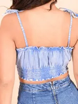 Crop top de jean celeste con breteles finos con lazos y detalle de frunce en el busto y en la cintura.