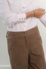 Camisa rosa pálido de algodón con cuello tipo masculino, abotonadura central, manga larga y puños con botones. Presenta canesú y cuello bordado con cadeneta a contratono.