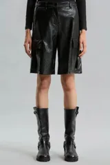 Bermuda de símil cuero brillante color negro, de calce relajado y tiro medio. Presenta bolsillos cargo laterales, bolsillos delanteros, pinzas traseras, presillas y broche delantero.