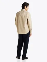 Camisa beige de corte amplio confeccionada en sarga de puro algodón teñido en prenda. Tiene cuello con botones, bolsillo de parche en el pecho y puños redondeados con botón.