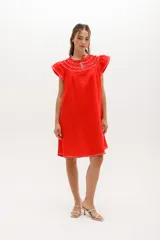 Vestido corto celeste de lino, corte suelto, con cuello redondo con volados y lazo, mangas cortas con volados.