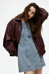 Vestido corto de denim azul, con escote redondo y cordones en el frente.