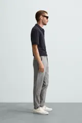 Pantalón largo de vestir gris claro con estampado de cuadros, corte slim fit y cintura elástica. Confeccionado en tejido con alta elasticidad, bolsillos frontales y cierre frontal con cremallera y botón.