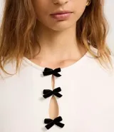 Blusa blanca de mangas cortas, confeccionada en Rib, con cuello redondo y lazos de terciopelo negros uniendo la abertura en la parte de abajo.