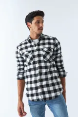 Sobrecamisa de algodón para hombre con interior de corderito, estampado a cuadros en tonos negro, blanco y azul. Tiene cierre de botones, bolsillos tipo cartera y logo en goma. El modelo usa talle M.