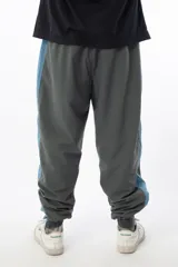 Pantalón de jogging gris con forro interno de red, bolsillos laterales con cierre, cierres en los tobillos y logo bordado.