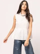 Top blanco de algodón con detalles bordados, largo a la cadera y con volado en la parte inferior.