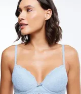 Soutien femenino modelo base con relleno hueco, confeccionado en encaje rústico. Posee tirantes finos ajustables y un pequeño lazo con medalla aplicada en el centro.