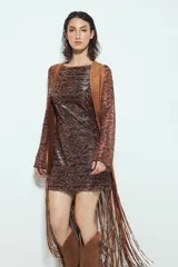 Chaleco largo color beige claro, estilo chaleco de gamuza, con apliques metálicos circulares perforados y largos flecos en el ruedo.