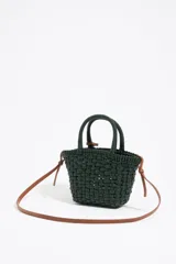 Bolso tipo tote de mimbre color marrón oscuro, con doble asa corta y correa de cuero marrón. Incluye dije circular dorado con letras grabadas.