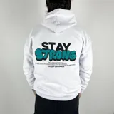 Canguro blanco oversize de algodón con felpa, con capucha y cordón ajustable. Estampa en la espalda con la frase "Stay Strong" en negro y turquesa, y texto inferior con la marca "Duxon Originals".