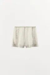 Shorts de tiro alto confeccionados en algodón color crudo, con cintura elástica, detalle de encaje, bordados y aplicación de abalorios a tono.