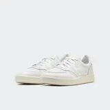 Championes New Balance modelo T-500, color blanco, confeccionados en nobuk y ante, con detalles perforados en la puntera, suela en espiga con círculo rotatorio y logo "N" en los laterales.