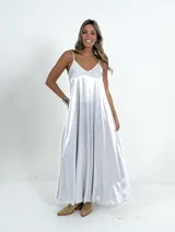Vestido italiano amplio con escote en V, confeccionado en tela nacarada con cuerpo que aporta estructura y movimiento.