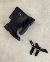 Bota de caña media de cuero negro con hebillas metálicas plateadas decorativas en la caña y alrededor del tobillo.