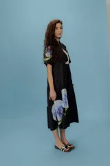 Vestido midi negro con estampado de flores y bichos en tonos celeste y blanco, con cuello camisero y botones frontales.