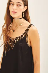 Top tipo musculosa confeccionado en modal satén, color negro, con terminación de calado en el escote delantero y en la espalda, acompañado de bordados a tono.
