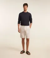 Bermuda de hombre en lino color gris claro, de corte recto, con textura discreta, bolsillos laterales y cierre frontal con botón y cremallera.