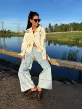 Campera de jean color manteca con apliques de flores de crochet en tonos neutros, corte recto y cierre con botones.