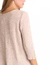 Buzo de tejido suave color beige, con cuello a la base y mangas 3/4 con aplique de botones dorados. Presenta terminación con tajos en los laterales.