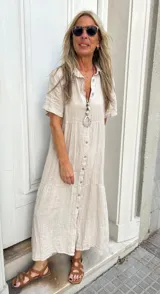 Vestido camisero midi color beige de lino, con cuello camisero, manga corta y abotonadura frontal.