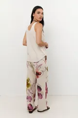 Pantalón de lino color celeste con estampado de flores grandes en tonos marrones, azules y rojos. El pantalón es de corte ancho y tiene cintura alta con cordón ajustable.