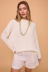 Buzo color crema tejido en algodón, de silueta holgada, mangas anchas y cuello bote.