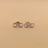 Par de aros pequeños con forma de infinito, realizados en plata 925 y adornados con circonias.