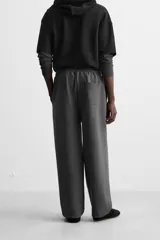 Pantalón jogger wide fit color gris oscuro, confeccionado en tejido de algodón compacto con elasticidad. Cuenta con cintura elástica ajustable con cordón, pliegues frontales, bolsillos delanteros y bolsillo trasero de parche.