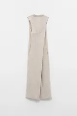 Vestido largo color beige, sin mangas, con cuello a la base y caída amplia. Confeccionado en tela estilo jogging.