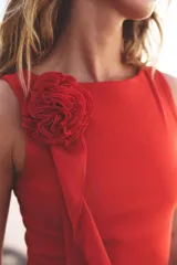 Top negro de cuello redondo y sin mangas, con detalle de flor con volumen en el hombro.