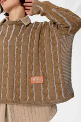 Sweater crop color crudo con rayas verticales negras y diseño de trenzas.