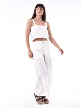 Pantalón ancho de tiro alto color blanco roto, con pliegues frontales y cierre de botones visibles en la cintura.