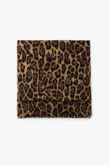 Pañuelo rectangular con estampado de leopardo en tonos marrón y negro, con terminaciones desflecadas.
